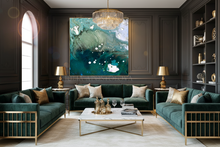 A large vertical canvas art print featuring an abstract teal, green, and white wave design, displayed on a dark wood paneled wall in a luxurious modern living room with green velvet sofas and gold accents.