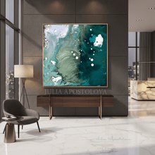 A large framed abstract wall art print hangs above a wooden console in a modern interior. The artwork features swirling teal, aqua, white, and dark green marbled patterns with a thin gold frame.