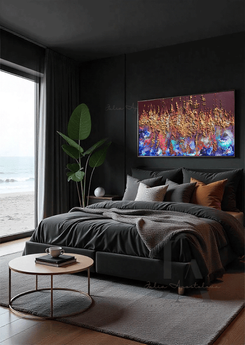 A modern dark bedroom, featuring a dark-grey, velvet bed, a low, round coffee table made of wood and gold metal, and a large colorful abstract painting with gold and copper rich 3d textures on the wall. The room overlooks a coastline through floor-to-ceiling windows. The setting sun casts a warm, natural glow across the scene.