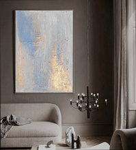 Abstract art piece on a wall in a living room with a chandelier and sofa.