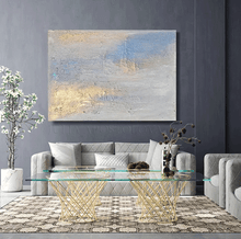 Modern living room with a glass coffee table, gray sofa, and abstract painting on a gray wall.