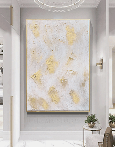 Abstract gold and white painting on a wall in a modern interior setting.