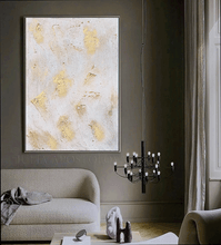 White Gold Minimalist Abstract art piece on a wall in a living room with a chandelier and sofa.