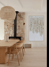 Dining room with wooden table, chairs, stone wall, and abstract art.