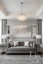 Living room with gray sofa, decorative pillows, and a large silver glitter abstract painting on the wall.