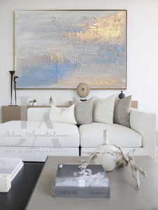 Modern living room with a large abstract painting above a white sofa.