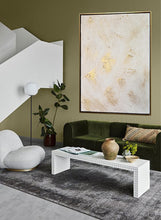 Modern living room with green sofa, white armchair, and abstract art on olive green wall.