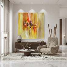 A large square abstract canvas art with expressive yellow, orange, red, and white brushstrokes, displayed in a modern living room setting above a console table.
