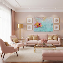 A styled living room featuring a large abstract canvas painting with vibrant pink, gold, and purple floral elements on a turquoise background, hung above a pink sofa with gold pillows.