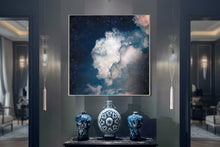 Decorative setup with a cloud-themed painting, blue vases, and a black console table in a room.