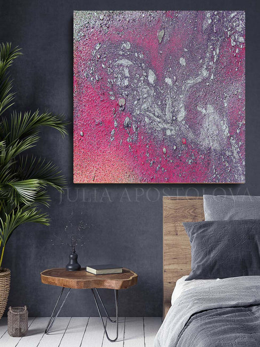 A canvas print featuring an abstract watercolor painting with silver accents, displayed above a bedside table in a cozy bedroom setting.