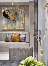 A contemporary abstract gold leaf canvas art hanging on a wall over a grey sofa with decorative cushions, with a focus on the artwork featuring gold leaf and metallic accents.